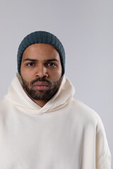 African American man in a knitted hat and white oversized hoodie.