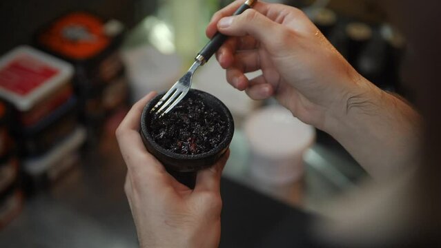 Horizontal view of the composition consisting of the embers and hookahs on the table is surrounded by thick smoke. The modern hookah is changing the colour.