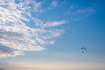 Paraglider in the blue cloudy sky, sunset, panorama, background
