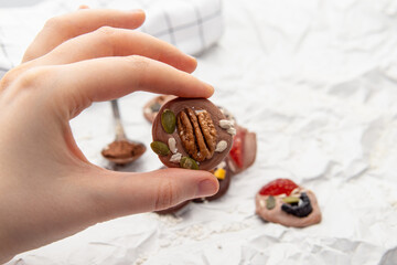 Woman or man holds french sweets. Handmade candies with nuts and berries. Space for text
