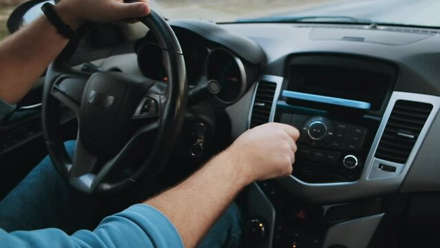 Hands unrecognizable Man driver control the radio or music on the road while driving a car in motion, slow motion video