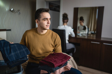 Man caucasian couple packing or unpack wardrobe cloth from suitcase at hotel room while his wife or girlfriend sit in background travel and vacation concept copy space