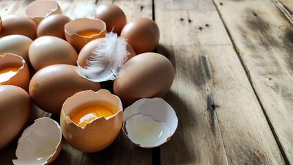 Many raw and fresh chicken eggs laid on a wooden table.