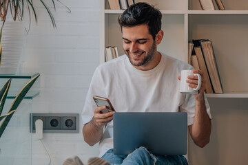 young man at home relaxed with laptop phone and cup of coffee