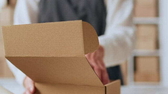 Manager in online store packs goods for delivery. Oversized hands of young women close box of clothes. Online purchase, product packaging, order to send for delivery. Promotion of sales and purchases
