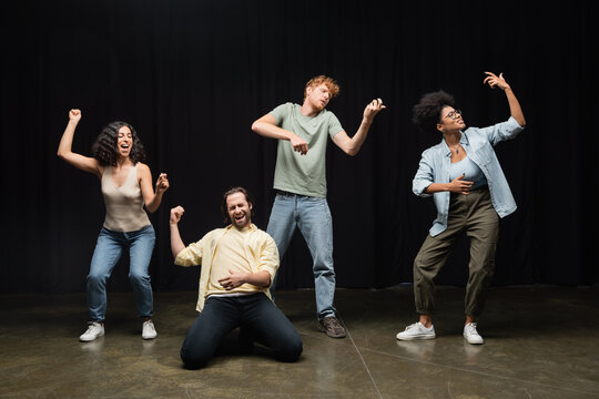 full length of young multicultural students rehearsing in various poses in acting skills school.