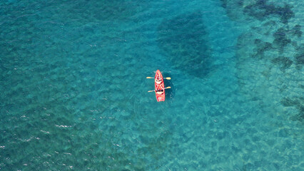 Aerial drone top down photo of red sport canoe as shot from above in turquoise clear sea