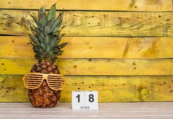 Creative june calendar planner with number  18. Pineapple character on bright yellow summer wooden...