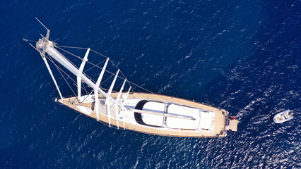 Aerial drone top down photo of beautiful sail boat with wooden deck anchored in deep blue...