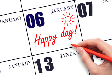 Hand writing the text HAPPY DAY and drawing the sun on the calendar date January 6