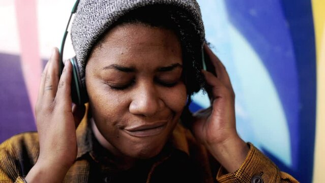 African woman listening music peaceful playlist with headphones outdoors - Urban culture lifestyle concept
