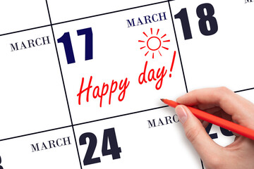 Hand writing the text HAPPY DAY and drawing the sun on the calendar date March 17