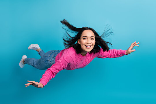 Full length photo of carefree adorable lady wear pink pullover arms wings flying air isolated blue color background
