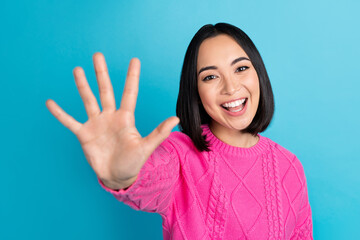 Portrait of pretty friendly malaysian lady arm palm waving hi demonstrate high five count isolated on blue color background