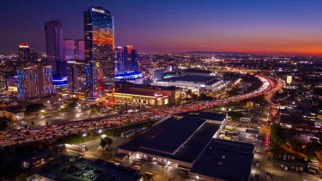 Urban aerial view or drone shot of busy downtown Los Angeles California in USA at night with freeway traffic and LA Convention Center time lapse.