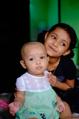 South asian little sisters are playing with each other, indoor family photo, friends playing with doll ,beautiful kids having fun