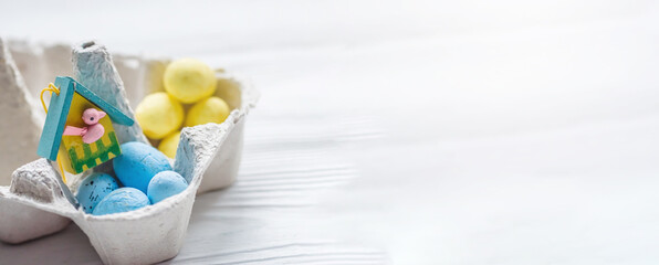 A bunch of yellow and blue eggs in egg carton. near the house with a bird. The concept of an abandoned home of Ukraine for the Easter holiday.