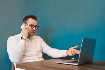 Businesswoman from Europe in glasses and white shirt talking on the phone gesticulating with his hands looking into a laptop