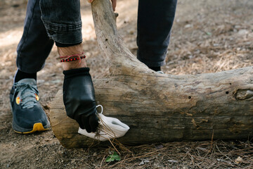 Boy collecting a mask in the forest under a log during a garbage collection to protect the planet