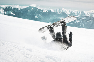 Snowboarder jump perform show off and ffall down on back on snowy day off-piste in Caucasus...