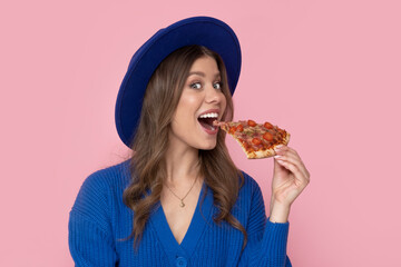Happy woman eat slice of pizza on pastel pink background with free space for text.