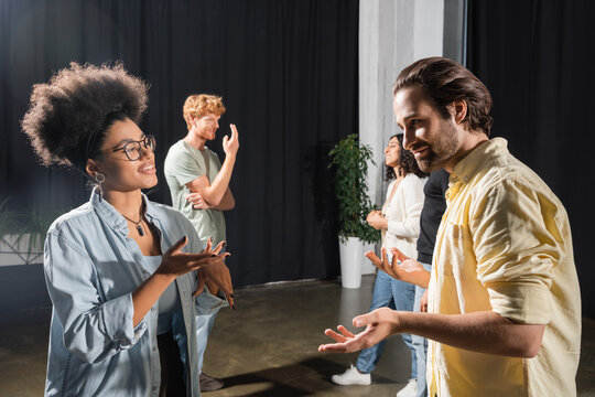smiling multiethnic actors gesturing during conversation in acting skills school.