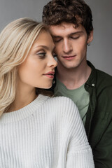Obraz premium portrait of curly young man with closed eyes near blonde woman in white sweater.