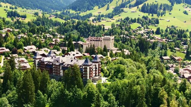 Drone Switzerland 4k. Gstaad Palace castle in Gstaad, Switzerland. Luxury ski resort town, upscale hotel. Swiss Flag. Beautiful Alps nature in summer. 