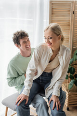 pleased young woman sitting with happy boyfriend on bed bench.