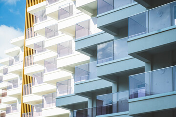 Fragment of white modern residential apartment house, hotel building with balconies on blue sky background