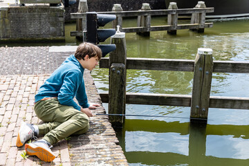 A teenager is fishing on a canal in Amsterdam