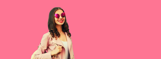 Portrait of beautiful smiling young woman wearing backpack on pink background