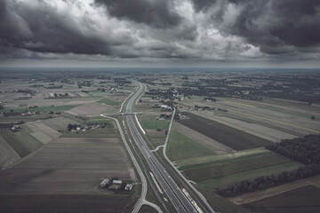 Diminishing aerial perspective of two-lanes highway under cloudy moody sky