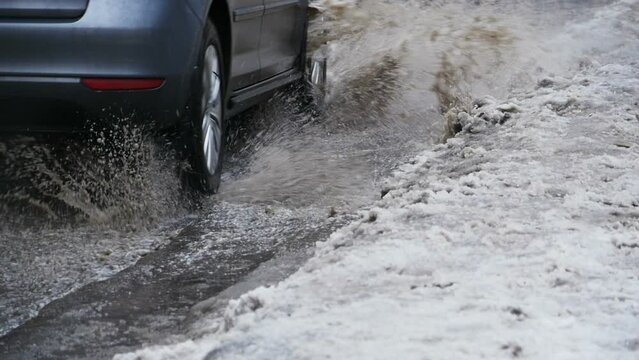 splashes from under the wheels of a car passing by, slow motion