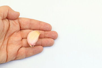 One hand holds a head of garlic on a white background
