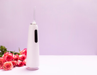 Dental discount, sale. holiday concept. Oral teeth irrigator, roses on purple background. Water...