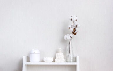 Air humidifier, figurine and vase with dried flowers on the white shelf. Minimalistic Scandinavian interior. Selecive focus, copy space
