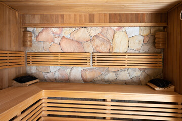 General view of sauna with wooden benches and stone wall