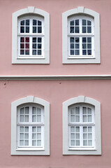 Fototapeta na wymiar Several windows in a row on the facade of the urban historic apartment building front view