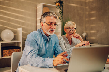 Senior couple online shopping with a laptop at home