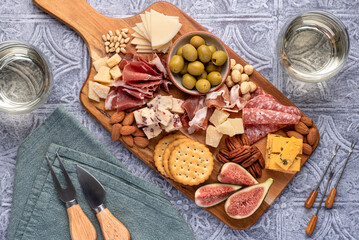 Food photography of white wine, salami, cracker, cheese, fig, parmesan, prosciutto, cheddar, olive, almond, nuts