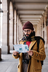 Young man checking city map in winter vacations, visiting historical European town 