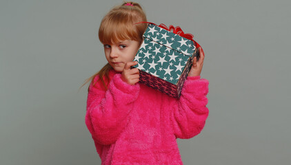 Happy toddler school girl receive, opening gift box and smiling joyfully, looking amazed satisfied with nice present unexpected birthday surprise. Teen female child kid isolated on gray background