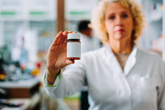 Pharmacist holding bottle of medicine.