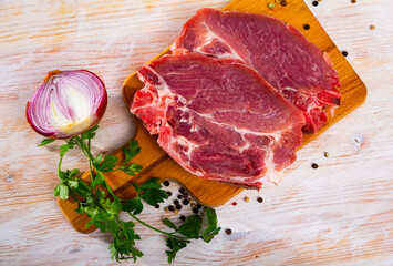 Fresh raw pork chop steak on wooden background with herbs