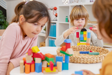 Obraz na płótnie Canvas Kindergarten children playing with colorful building blocks. Healthy learning environment. Learning through play.