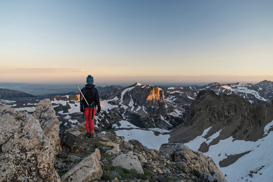 Rear view of hiker standing on mountain against sky during sunset