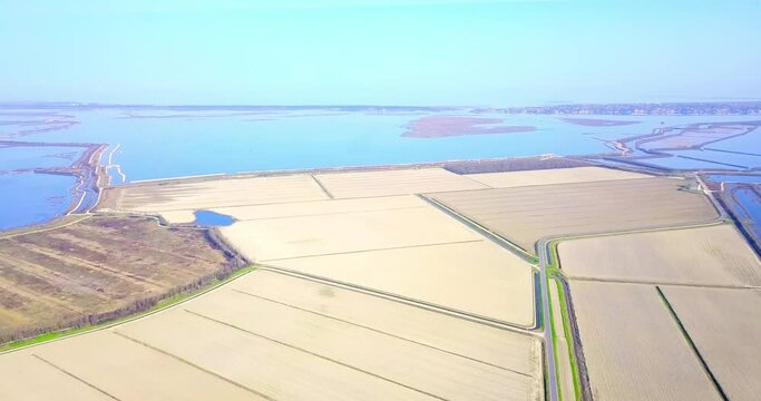 Wonderful blue lagoon nature near narrow ennobled polders and boundless plowed unseeded fields on warm sunny day aerial view