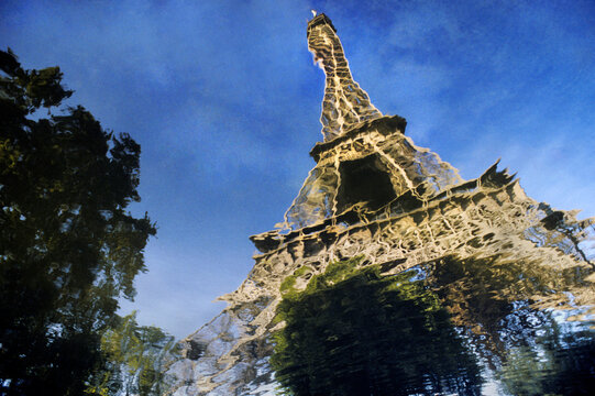 The Eiffel Tower in Paris France reflected in a pool of water left behind by a rain storm.