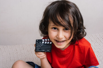 Little boy holding a with a movie clapperboard